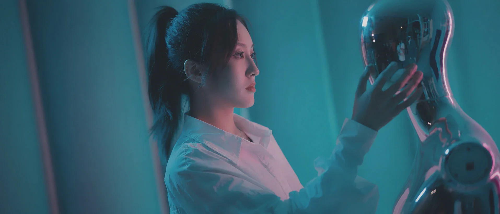 女孩伸手轻触镜面机器人的面部,彼此对望。